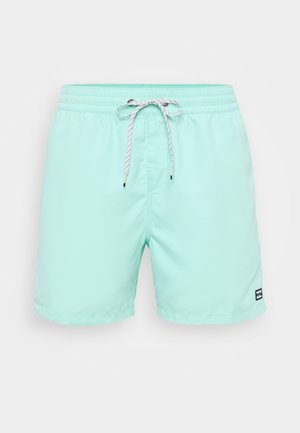 Gaišs mišu zaļās peldbikses ar elastīgu jostu, baltu sasaistes auklu un mazu melnu logo apakšējā labajā stūrī.