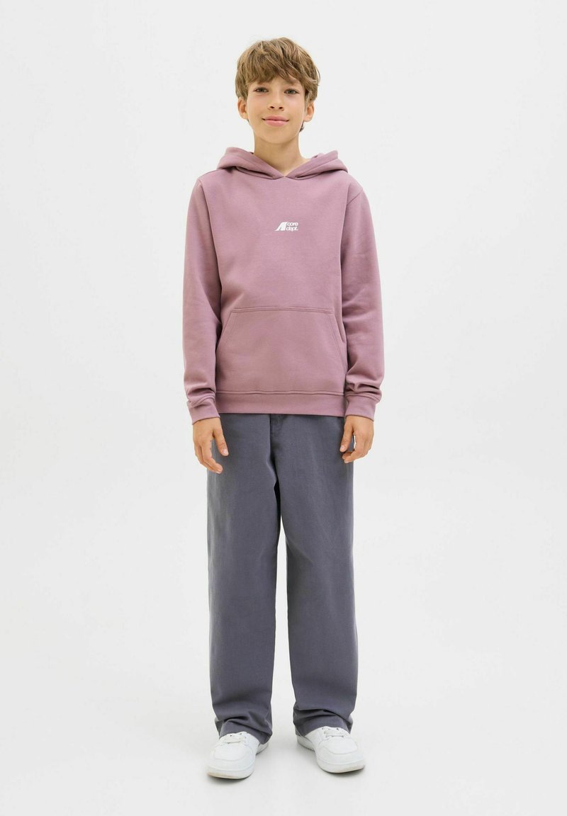 Roze hoodie met een buidelzak en wit logo, gecombineerd met grijze wijde broek en witte sneakers, gepresenteerd op een effen witte achtergrond.