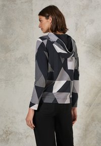 Hoodie met een geometrisch patroon in zwart, grijs en wit. Gemaakt van zachte stof met een relaxte pasvorm en lange mouwen.