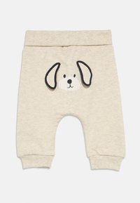 Παντελόνια μπεζ ανοιχτού χρώματος για νήπια με σχέδιο προσώπου σκύλου με μαύρες περιγράμματα, ριμπ ζωνάκι μέσης και μανσέτες. Μαλακό, άνετο ύφασμα.