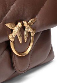 Bruine leren handtas met een gequiltde textuur, met een gouden sluiting in de vorm van twee vogels en een metalen ring.