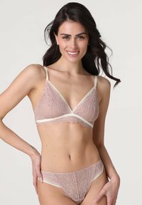Bralette in pizzo e mutandine coordinate in rosa chiaro con accenti crema. Il reggiseno presenta un design triangolare con delicate decorazioni in pizzo.
