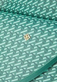 Groene, gemarmerde portemonnee van gestructureerd synthetisch materiaal met een gouden logo-accent. Bevat geometrische ontwerpen in verschillende tinten groen.