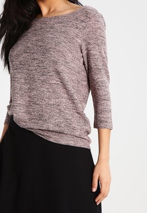 Haut en tricot dans des teintes de rose et de gris, avec une coupe décontractée, un col bateau et des manches trois-quarts. Associé à une jupe noire.