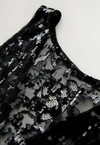 Schwarzer Spitze-Stoff mit silbernen Pailletten in einem komplizierten Muster, mit einem runden Ausschnitt und einer weichen, strukturierten Oberfläche.