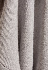 Grijs gebreide stof met een zachte textuur, met lichte variaties in dikte en een glad oppervlak. Minimalistisch en neutraal ontwerp.