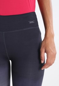Leggings a vita alta, di colore blu navy, con una texture liscia, caratterizzati da cuciture a contrasto e un piccolo logo "Venice Beach" sulla vita.