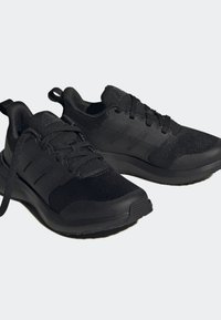 Svarta träningsskor gjorda av mesh och syntetiska material, med ett mönstrat ovandel, snörningsstängning och en dämpad sula för komfort.
