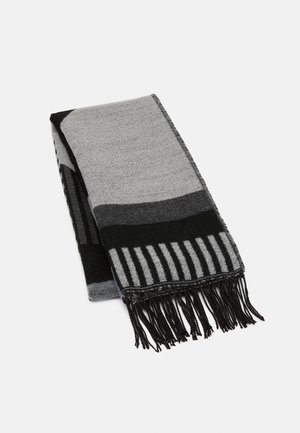 Écharpe pliée avec des motifs géométriques noirs et gris et des bords à franges sur fond blanc.