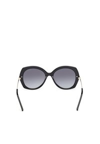 Gafas de sol grandes y negras con un diseño geométrico, lentes degradados y acentos en metal de tono dorado en las patillas. Montura de plástico suave.