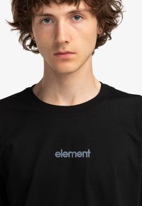 Camiseta de algodón negra con un logo "element" en gris claro en el frente, con un cuello redondo clásico y mangas cortas.