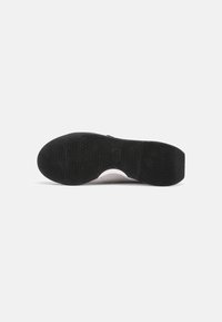 Black rubber sole with textured pattern and a white midsole. The design is minimalist, with smooth edges and a clean silhouette.