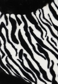 Teflon de blană artificială cu dungi îndrăznețe în alb și negru, având o textură moale și pufoasă. Designul include lățimi variate ale dungilor.