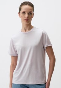 T-shirt di colore viola chiaro realizzato in tessuto morbido e liscio. Presenta maniche corte, collo a giro e una vestibilità rilassata. Design minimalista.
