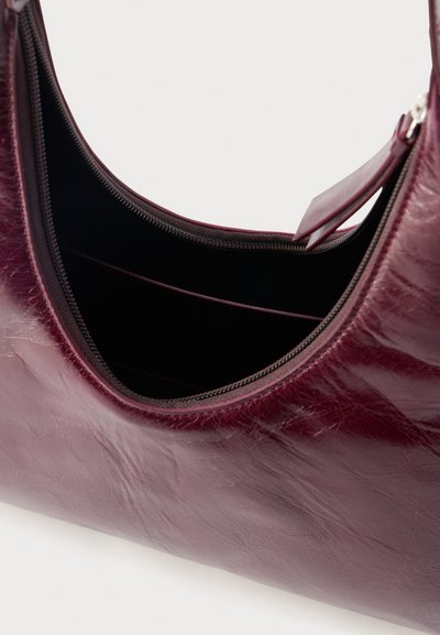 Sac à main en cuir bordeaux foncé avec une fermeture éclair sur le dessus et des emplacements pour cartes à l'intérieur, présenté ouvert pour révéler les compartiments intérieurs.