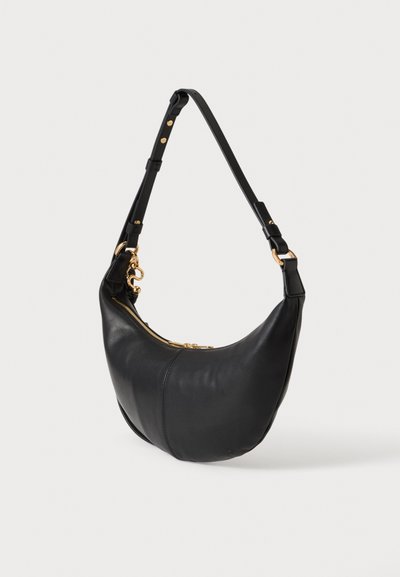 Sac à épaule en cuir noir avec bandoulière réglable, fermeture éclair et accessoires métalliques dorés, présenté sur un fond clair uni.