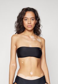 Crni bandeau bikini gornji dio s glatkom teksturom, dizajn nema naramenica, a na prednjoj strani se nalazi mali logotip.
