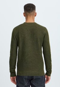 Olijfgroen trui van gebreide stof. Heeft een ronde hals, lange mouwen en een geribde zoom. Textuurfinish met subtiele kleurvariaties.
