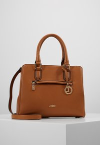 Sac à main en cuir marron texturé avec deux poignées supérieures, bandoulière amovible, poche avant zippée et un pendentif logo doré en accent.