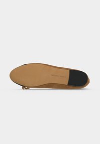 Semelle d'une chaussure plate en daim marron avec talon et grip en caoutchouc texturé, et "Steve Madden" embossé près du talon.