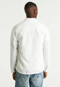 Witte lange mouw overhemd met knoopmanchetten, voorzien van een gestructureerde stof en een afgeronde zoom. Standaard kraag en minimalistisch ontwerp.