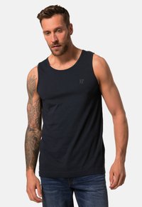 Marineblå bomulds tanktop med rund halsudskæring og et subtilt logo på brystet. Pasformen er afslappet, og den bæres med denim jeans.