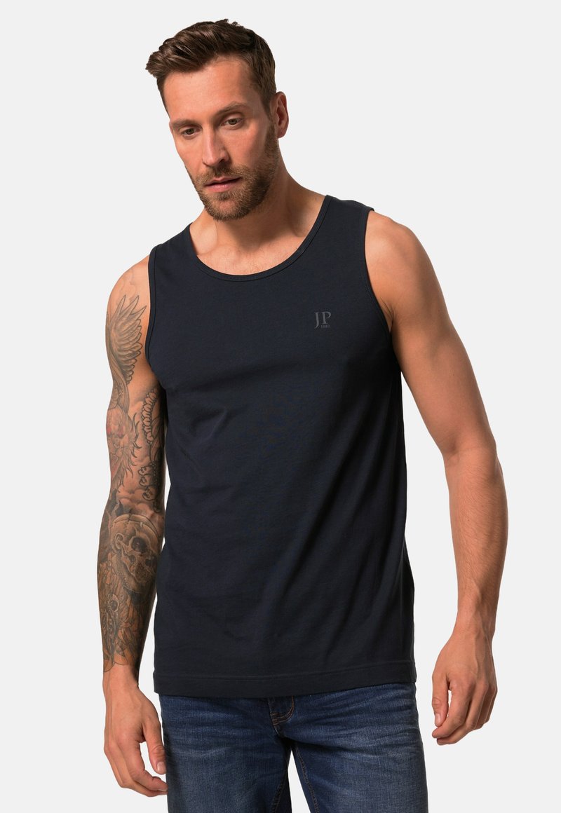 Marineblå bomulds tanktop med rund halsudskæring og et subtilt logo på brystet. Pasformen er afslappet, og den bæres med denim jeans.