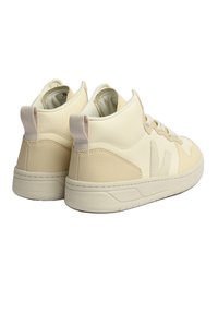 Beige lädersneakers med strukturerad yta, snörningsdesign och dragflikar på hälen. Har mörkare beige detaljer och en tjock sula.