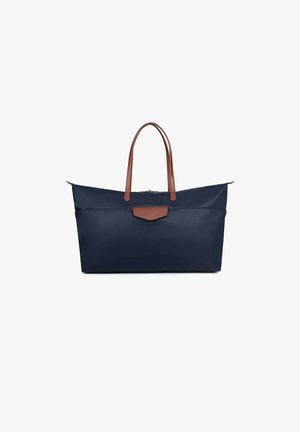 Navy blue tote bag with brown leather accents and handles, featuring a minimalist design, smooth texture, and a zippered closure.