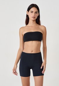 Top senza maniche nero e pantaloni corti a metà coscia realizzati in tessuto traspirante. Design semplice con bordi senza cuciture e vestibilità comoda.