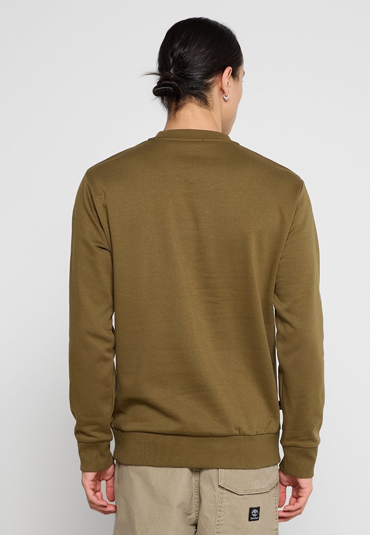 Felpa verde oliva con colletto rotondo, maniche lunghe e polsini e orlo a costine. Tessuto liscio, indossata con pantaloni chiari.