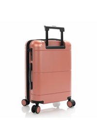 Valigia da cabina rigida in oro rosa, dotata di manico telescopico, doppie ruote e lucchetto combinato per la sicurezza. Texture liscia.