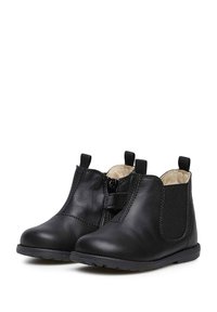 Botas negras de cuero hasta el tobillo con cremallera lateral, detalles elásticos y textura suave. Puntera redondeada y suela de goma resistente.