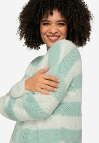 Cardigan a righe verde menta e bianco, lavorato a maglia, con maniche lunghe e texture morbida, caratterizzato da una vestibilità ampia e polsini a costine.