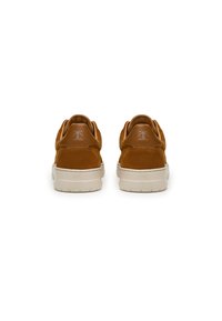 Sneaker in suede marrone con suola in gomma bianca, dotate di un tassello sul tallone in pelle liscia e di un brand minimale sul retro.
