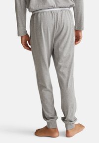Pantalones de pijama grises hechos de una tela suave, con una banda elástica en la cintura que lleva la marca "UNITED COLORS OF BENETTON" y tobillos ajustados.