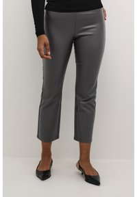 Pantalones cortos de imitación cuero gris con una textura suave, detalles de costura y un ajuste ceñido, combinados con tacones de charol negros de tipo slingback.