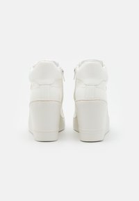 Sneakerii albi cu toc înalt, cu un exterior sintetic neted, guler căptușit și două fermoare la spate pentru acces ușor.