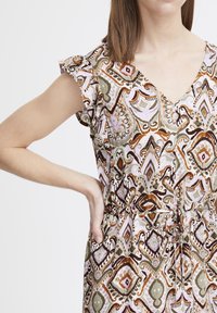 Robe à manches courtes à motifs dans des tons de rose, vert et marron. Elle présente un col en V, des manches à volants et une taille élastique avec cordon de serrage.