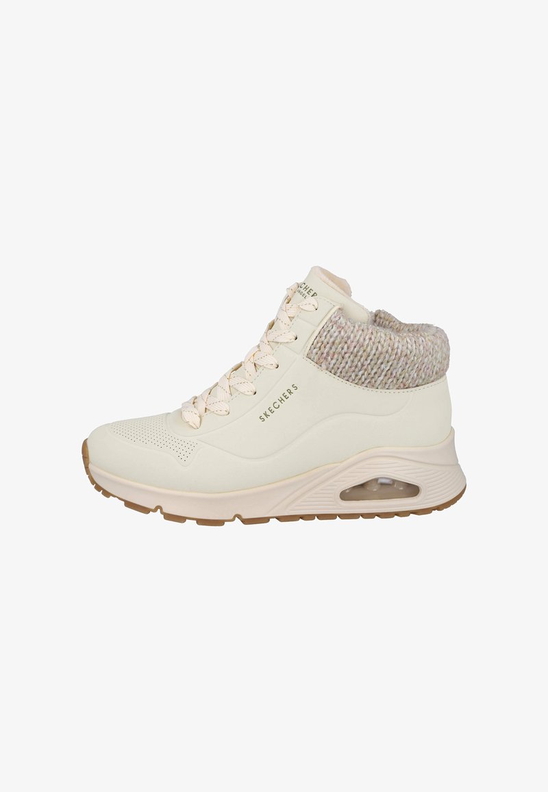 Zapatilla alta en crema con un cuello de punto texturizado. Cuenta con una punta perforada y una suela acolchada con una unidad de aire visible.