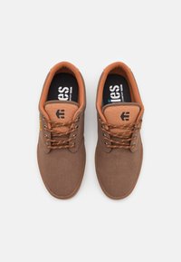 Baskets en toile marron avec des accents marron clair, bout rond, lacets marron et semelles intérieures noires avec logo de la marque blanc.