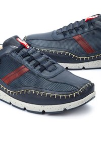 Sneakers blu navy con tomaia in pelle e perforata, con accenti rossi, cuciture beige e una suola bianca testurizzata.