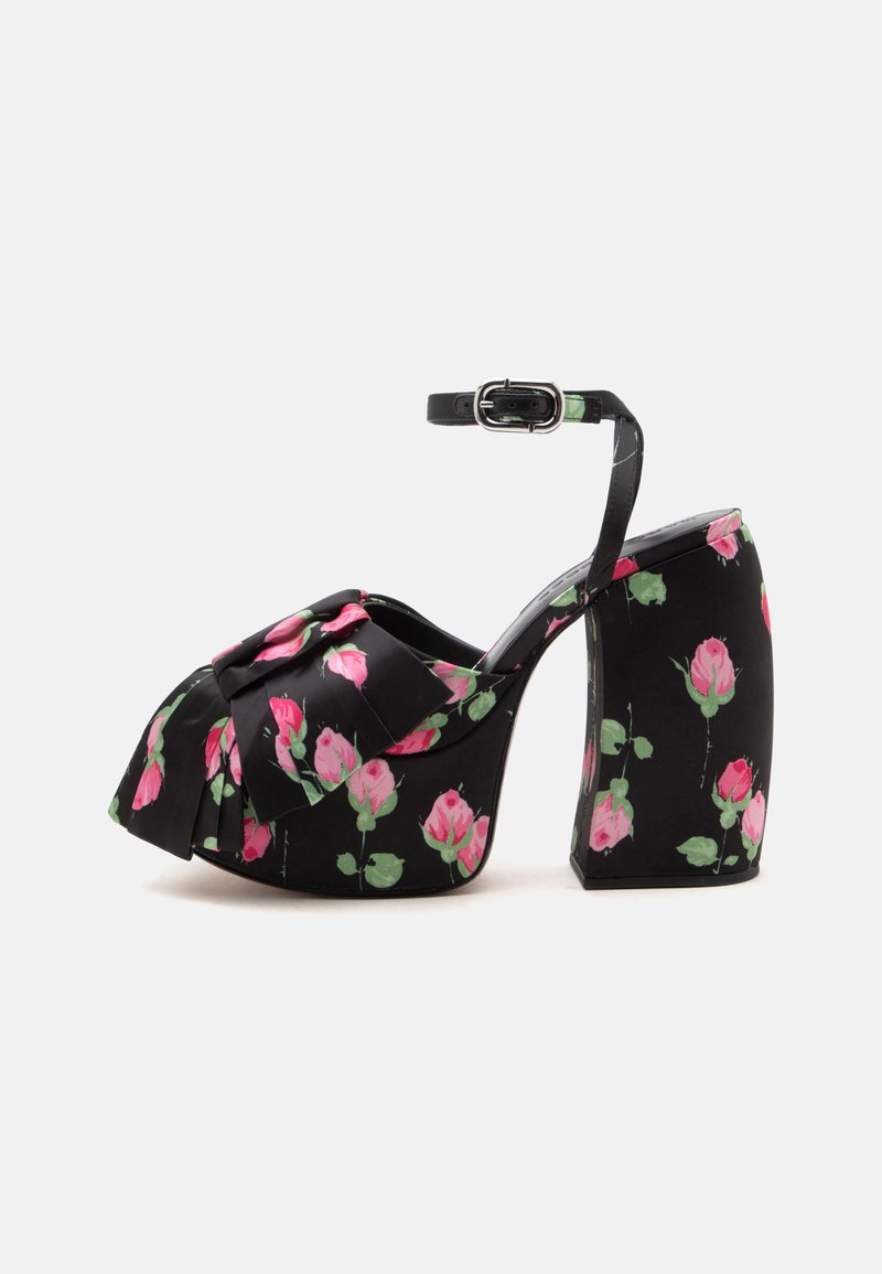 Sandale à talon haut plateforme noire avec bride à la cheville et motif floral de rose rose, avec un grand nœud sur la zone des orteils.