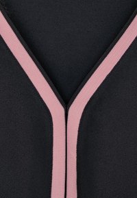 Svart zippered plagg med V-ringning, som har en kontrasterande rosa texturerad dragkedja längs nacköppningen. Slät tygfinish.