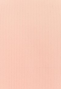 Rippstrickstoff in zartem Rosa mit einem vertikalen Linienmuster, das eine strukturierte Oberfläche mit einem gleichmäßigen, glatten Erscheinungsbild schafft.