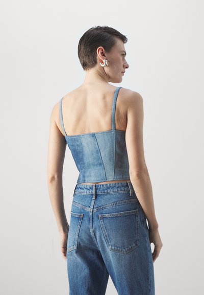 Denim avkortet topp med tynne stropper i lyseblå, med et tettsittende liv og rett kant. Kombinert med matchende høy midje jeans.