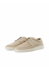 Zapatos de ante beige con un diseño de perfil bajo, punta redonda y suela de goma blanca. Cuentan con cordones y detalles de costura a lo largo de la parte superior.