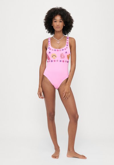 Ροζ ολόσωμο μαγιό με τετράγωνη λαιμόκοψη, διακοσμημένο με πολύχρωμες εφαρμογές κοχυλιών και λουλουδιών γύρω από την περιοχή του στήθους. Λείος υφασμάτινος σχεδιασμός.