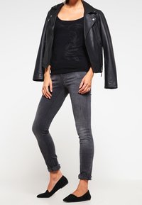 Musta nahkainen moottoripyörätakki mustan toppat-paidan päällä, harmaiden slim fit -farkkujen ja mustien ballerinojen kanssa. Yksinkertainen, hyvin istuva muotoilu, jossa on käärityt hihansuut.