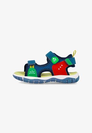 Sandalia infantil de punta abierta con malla azul, detalles en rojo y verde, lengüeta amarilla y suela gruesa gris, mostrada en perfil izquierdo.